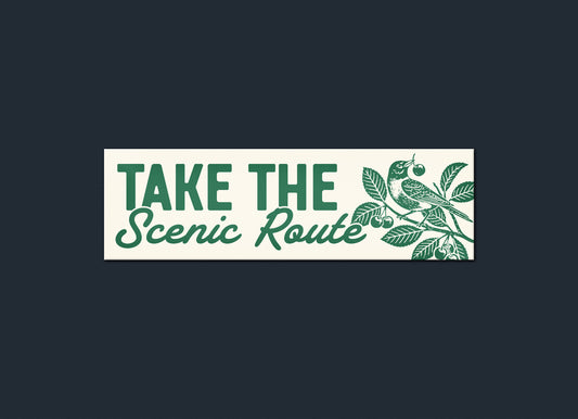 Decorative sign with 'Take the Scenic Route' text and nature-themed design on a dark background